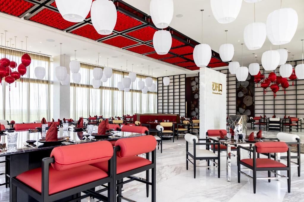 Un restaurant moderne, décoré de rouge et de blanc, avec des tables et des chaises disposées pour accueillir les clients.
