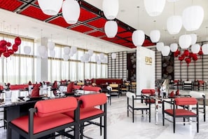 A modern restaurant with red and white decor, featuring tables and chairs arranged for dining. - Garza Blanca Resort and Spa - All Inclusive (Punta Sam)