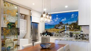 A modern kitchen with a wooden dining table, a large island with a built-in stove, and a large window with a scenic view. - Garza Blanca Resort and Spa (Punta Sam)