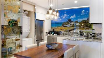 Una cocina moderna con una mesa de comedor de madera, una isla grande con estufa integrada y un ventanal con vistas panorámicas.