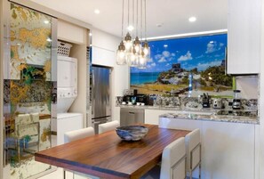 Una cocina moderna con una mesa de comedor de madera, una isla grande con estufa integrada y un ventanal con vistas panorámicas.