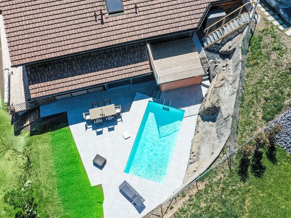 Vista aérea de una propiedad residencial con piscina, mobiliario de patio y una zona exterior cubierta.