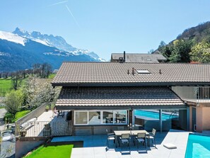 Una casa moderna con un amplio patio, piscina y vistas a la montaña.