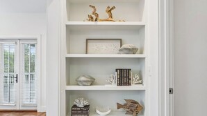 A white shelving unit with various decorative items and a framed picture. - Magnolia Cottages on 30A: 5-Min Walk to the Beach! 2 King Beds, Bunk Room (Inlet Beach)