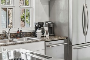 Eine moderne Küche mit einem Edelstahl-Kühlschrank, einer Kaffeemaschine und einem Spülbecken.