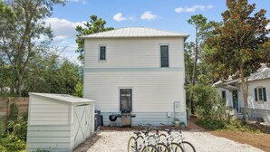 A two-story house with a garage and a covered area with bicycles. - Magnolia Cottages on 30A: 5-Min Walk to the Beach! 2 King Beds, Bunk Room (Inlet Beach)