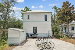 A two-story house with a garage and a covered area with bicycles. - Magnolia Cottages on 30A: 5-Min Walk to the Beach! 2 King Beds, Bunk Room (Inlet Beach)