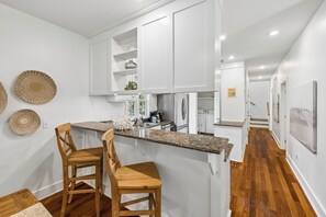 Eine moderne Küche mit weißen Schränken, Granit Arbeitsplatten und Holzhockern.