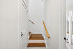Eine Treppe mit Holzboden und Geländer, die zu einer Empfangshalle mit einer weißen Tür führt.