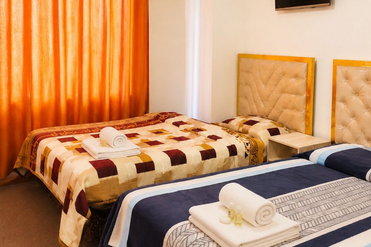 Habitación de hotel con dos camas, un televisor de pantalla plana y un candelabro.