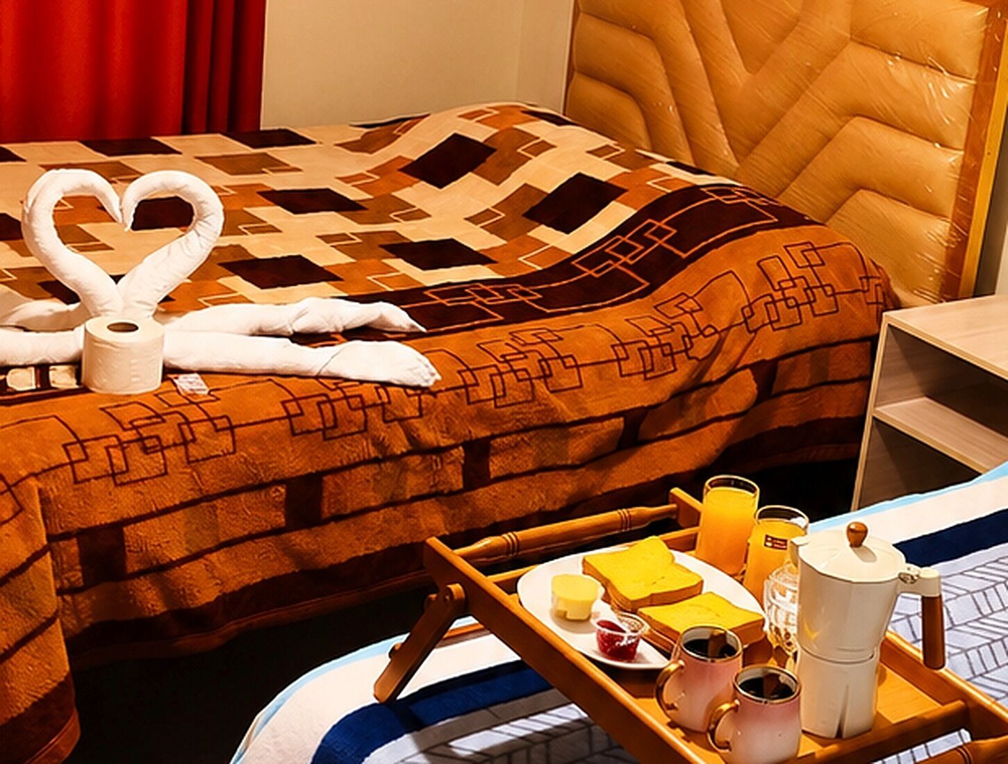 A hotel room with a bed, a tray with breakfast items, and a headboard.