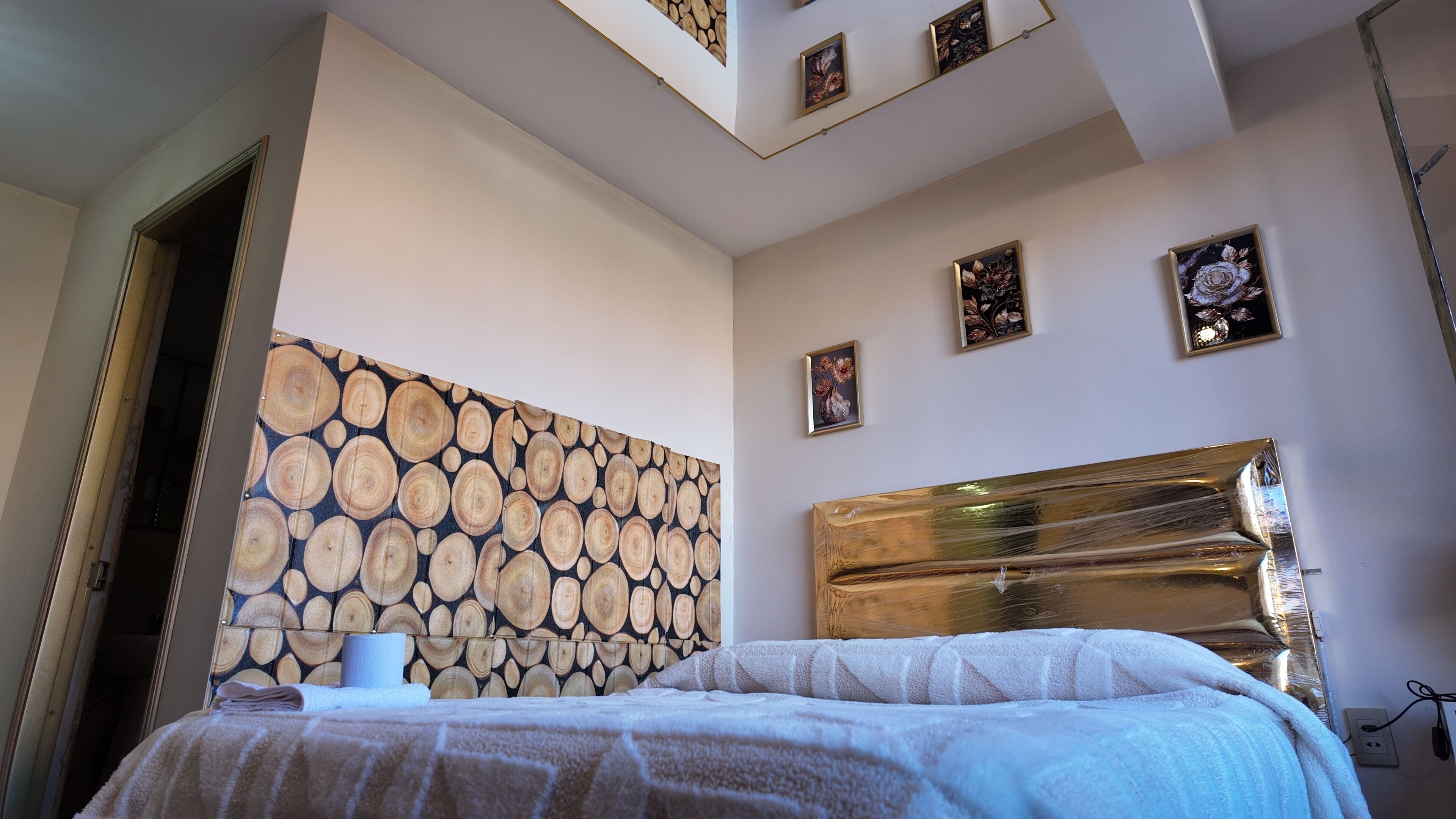 Un dormitorio con cabecera, cama, pared con diseño de madera e iluminación empotrada en el techo.