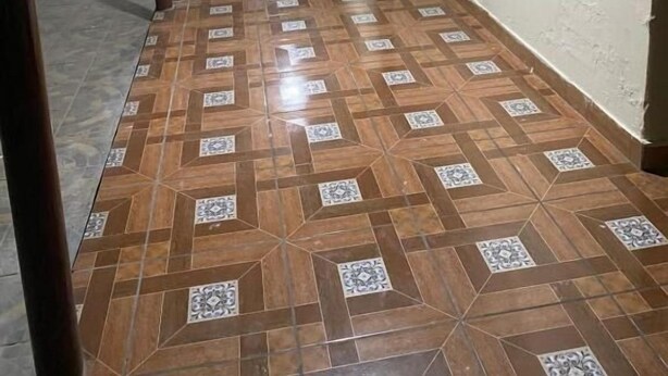 Un pasillo con piso estampado, techo con iluminación empotrada y un logotipo montado en la pared.