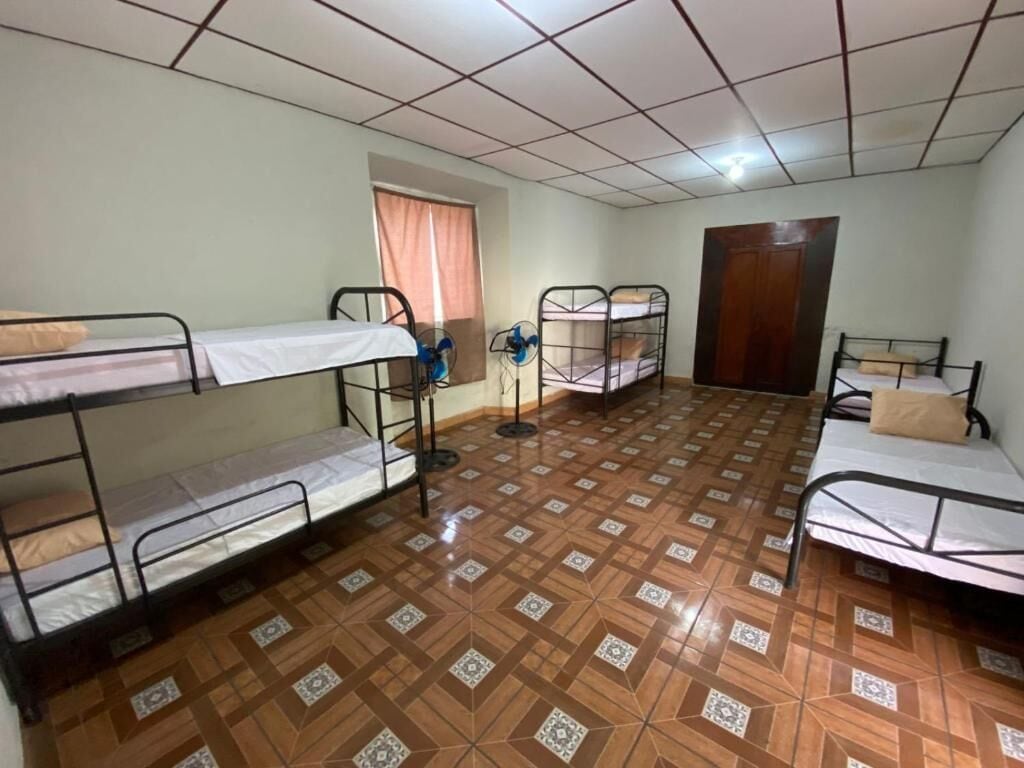 Um dormitório com beliches, um ventilador e uma porta.