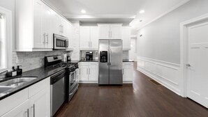 Una cucina moderna con mobili bianchi, elettrodomestici in acciaio inossidabile e pavimento in legno scuro.