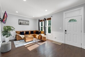 Ein Wohnzimmer mit einer Eckcouch, einer Topfpflanze und einem Stadtbild.