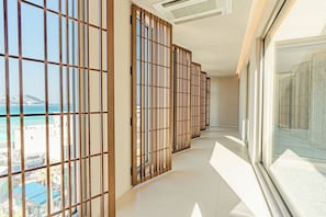 A corridor with sliding wooden doors leading to a balcony with a view of the sea. - KONST HOTEL (Jeju City)