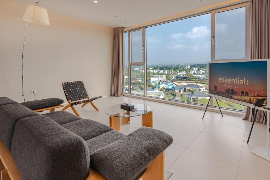 Una sala de estar moderna con un sofá, una silla, una mesa de centro y una pantalla de televisión que muestra la palabra 'essential' en la pared.