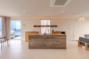 A modern kitchen with a central island, wooden cabinets, and a view of the ocean.