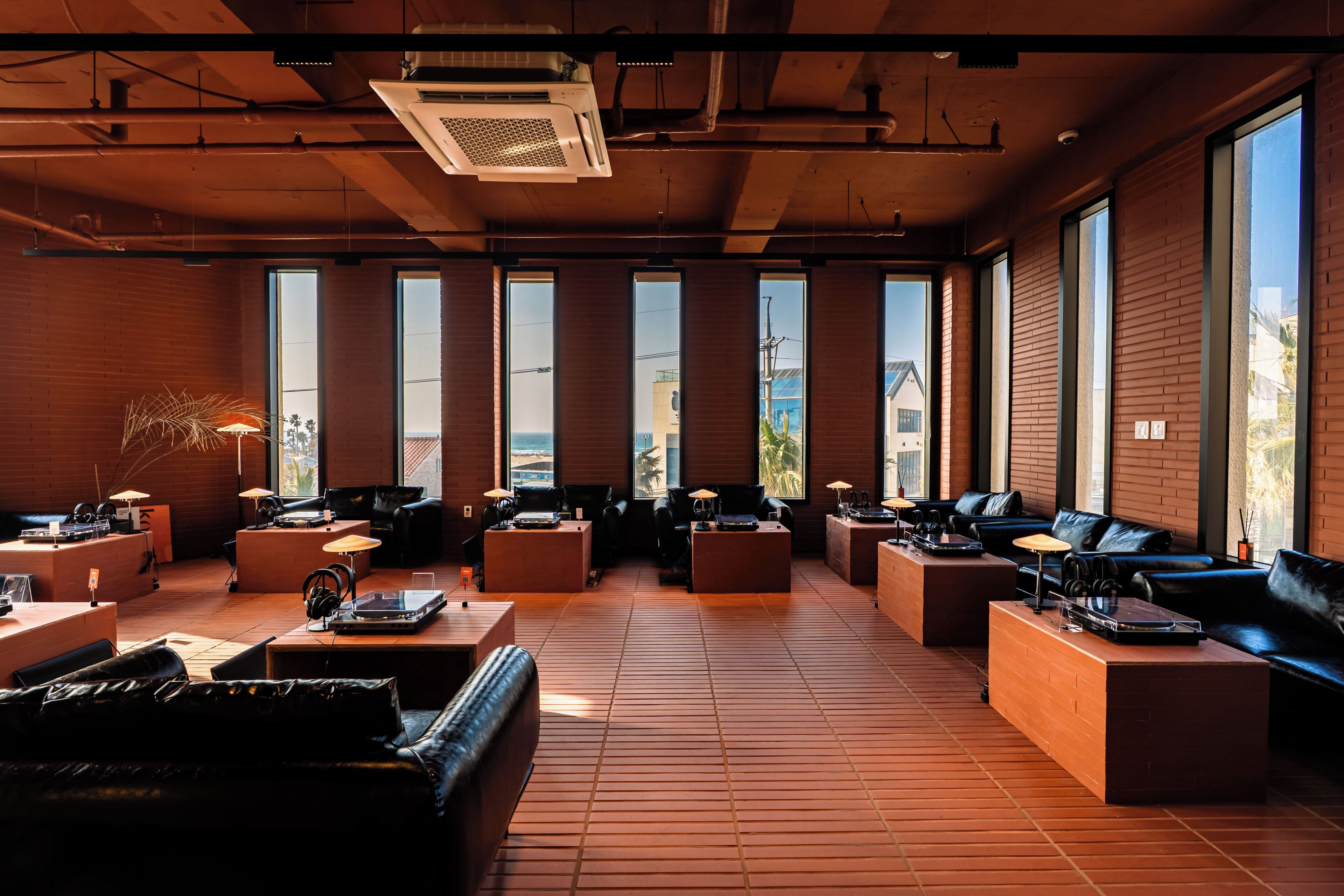Amplia sala de estar con diversas opciones de asientos, ventanas grandes y un diseño industrial moderno.