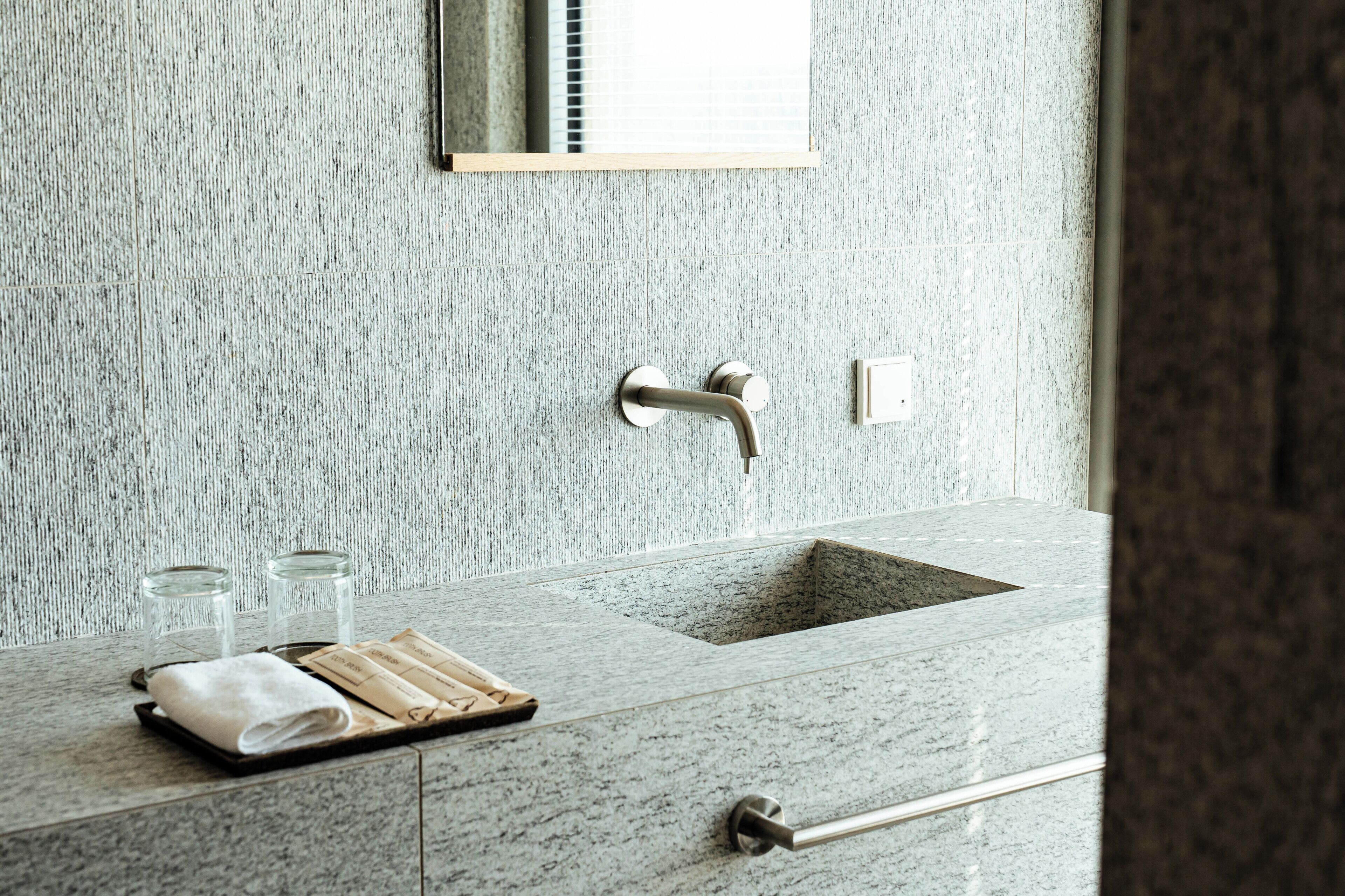 A bathroom with a marble sink, a towel, and a glass.