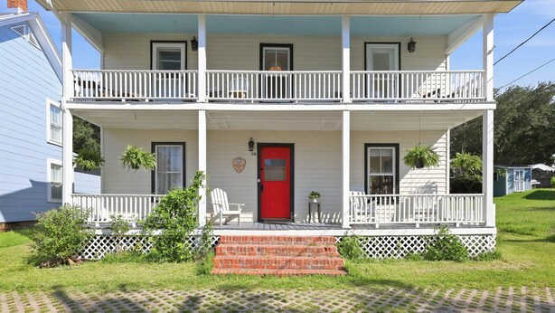 A two-story house with a red front door, white railings, and a covered porch. - Historic Swansboro Retreat- 3-bedrooms- Water Views & Spa Bath (Swansboro)