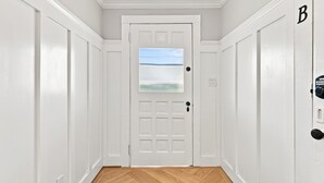 A hallway with a white door, a window with a view, and a doorbell. - Historic Swansboro Retreat- 3-bedrooms- Water Views & Spa Bath (Swansboro)
