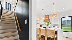 A modern kitchen with a central island, pendant lighting, and a view of the outdoors through large windows. - Historic Swansboro Retreat- 3-bedrooms- Water Views & Spa Bath (Swansboro)