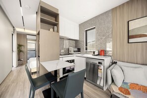 A compact kitchen with a dining area, a built-in microwave, a coffee maker, and a dishwasher.