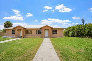 A single-story house with a front porch, a garage, and a well-maintained lawn. - Comfy 2 Bed 1 bath with a fenced backyard  family home (Fort Myers)