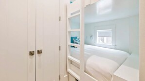 Ein Zimmer mit einem Etagenbett, einem Fenster mit Jalousien und einer Tür mit Griff.