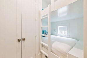 Ein Zimmer mit einem Etagenbett, einem Fenster mit Jalousien und einer Tür mit Griff.