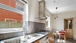 A kitchen with a built-in washing machine, a gas stove, and a sink. - 3BR Victorian Home for Up to 5 Guests (West Northamptonshire)