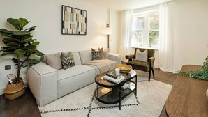 Un salon moderne comprenant un canapé, un fauteuil, une table basse et une grande plante.