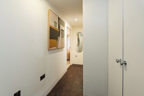 Ein Flur mit Holzboden, einer weißen Tür und einem Gemälde an der Wand.