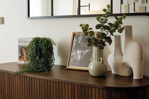 A wooden console table with a framed photograph, a green plant, and two white vases. - 2BR Duplex Flat near Buckingham Palace (London)