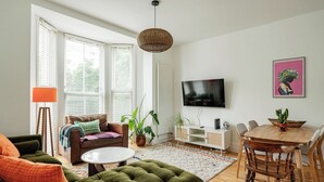 Un salon comprenant un canapé, une table basse, un téléviseur et un coin repas avec des chaises et une table.