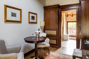 A room with a round table, two framed pictures on the wall, a lamp, and a view of the outside. - Villa Lampina - private villa on luxury estate (Varignana-Palesio)