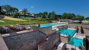 A pool area with multiple swimming pools, outdoor seating, and a stone wall. - Villa Lampina - private villa on luxury estate (Varignana-Palesio)