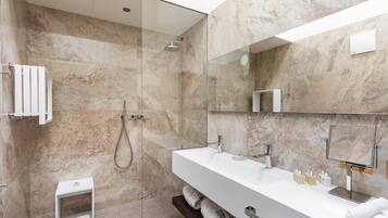A modern bathroom with a glass-enclosed shower, a large mirror, and a white vanity with multiple sinks.