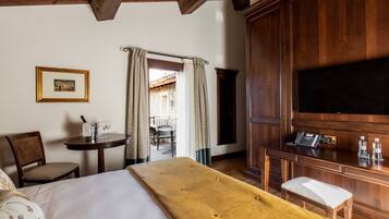 A hotel room with a bed, a desk with a telephone, a chair, and a table with a wine glass.
