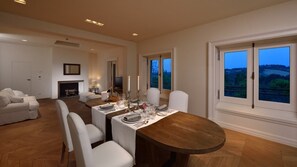Ein Essbereich mit einem Holztisch, gedeckt für vier Personen, weißen Stühlen und Blick auf die Landschaft durch große Fenster.