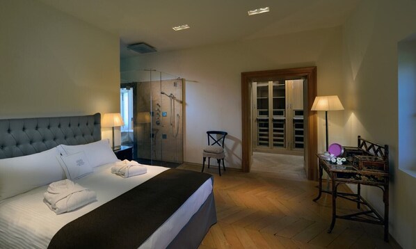 Une chambre d’hôtel comprenant un lit, une chaise, une table avec quelques objets, une armoire et un espace douche.