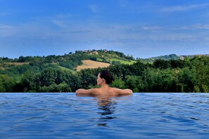 Eine Person entspannt sich in einem Whirlpool mit Blick auf eine üppige grüne Landschaft.