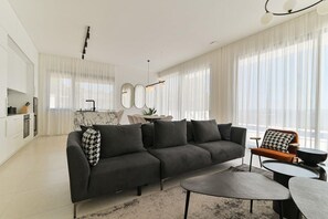 Ein modernes Wohnzimmer mit einem Ecksofa, einem Couchtisch und einem Essbereich mit Tisch und Stühlen.