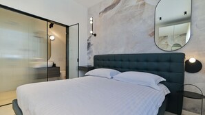 A modern bedroom with a large bed, a glass partition, a mirror, and wall-mounted lights. - Villa Basia with private pool in Ciovo Island (Okrug Gornji)