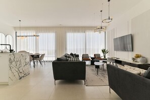 A modern living room with a sofa, chairs, a dining area, and a kitchen with a marble island. - Villa Basia with private pool in Ciovo Island (Okrug Gornji)