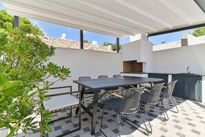 An outdoor patio with a table and chairs, a built-in grill, and a view of the surrounding landscape. - Villa Basia with private pool in Ciovo Island (Okrug Gornji)