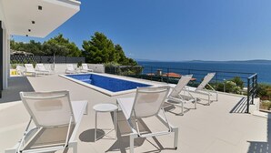 A rooftop pool area with lounge chairs and a view of the sea. - Villa Basia with private pool in Ciovo Island (Okrug Gornji)