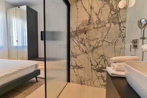 Ein modernes Hotelzimmer mit einem Bett, einem Badezimmer mit einer Badewanne und einer Glasabtrennung.